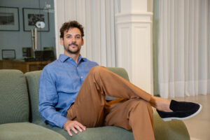 Joaquín Basanta, joven empresario argentino, sentado con actitud relajada en una oficina moderna, tras recibir un premio internacional por su trabajo en producción agrícola sustentable.
