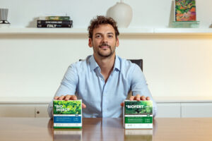 Joaquín Basanta, fundador de Agro Sustentable, sostiene los bioinsumos BIOINSECT y BIOFERT en una oficina moderna, símbolo de innovación agrícola y sostenibilidad.