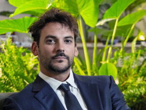 Joaquín Basanta, empresario argentino del sector agroecológico, con traje formal frente a un fondo verde natural.