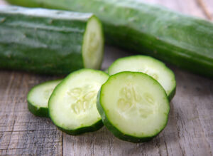 Rodajas de pepino fresco sobre una tabla de madera, ideal para destacar su calidad y propiedades en producciones orgánicas.